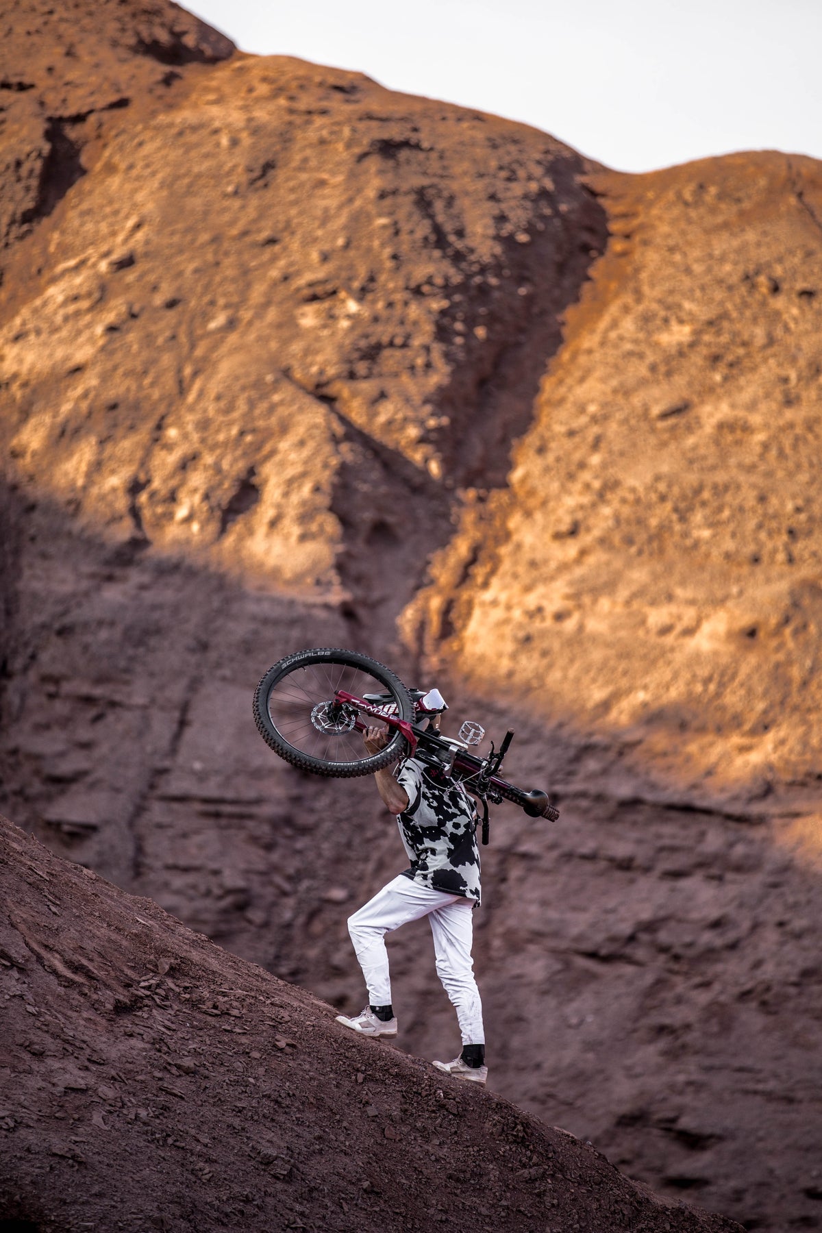 DEVOL rider con pantalón MTB blanco cargando la bici en el cerro